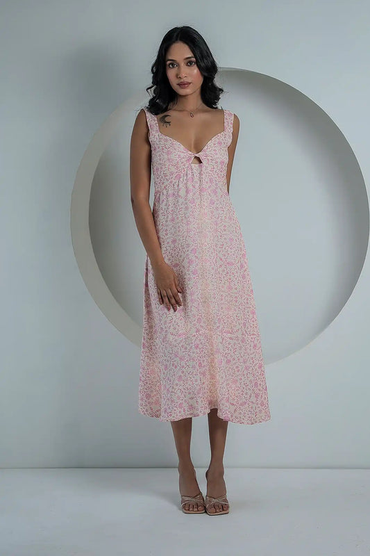 Full-length view of a woman wearing a sleeveless, fondant pink floral print midi dress with a sweetheart neckline, posed against a minimalist white circular backdrop.