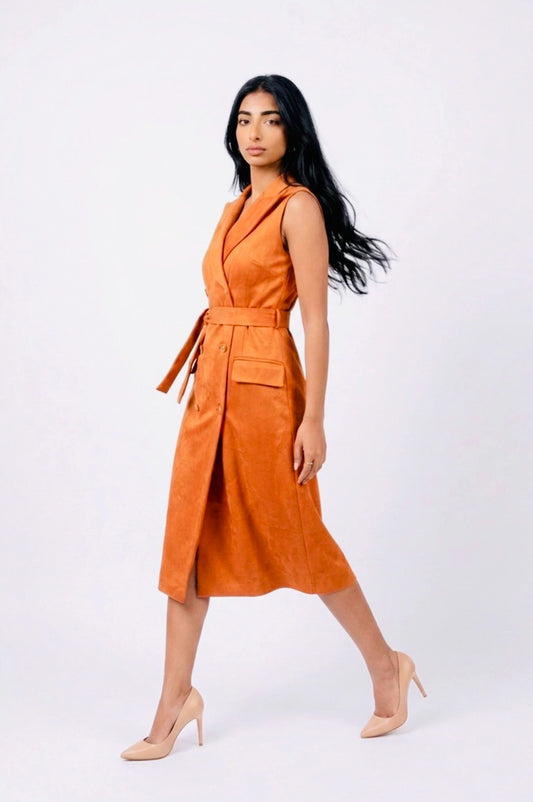Side view of a model walking in a sleeveless rust orange suede trench dress with light skin colour high heels.