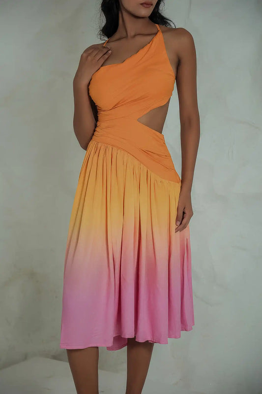 Front three-quarter view of a model wearing an asymmetrical mandarin orange to fondant pink sunset gradient dress with a flattering side waist cut-out and draped bodice.