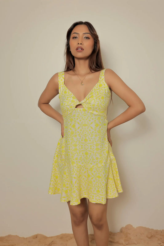 Front view of a model wearing the Tea & Dove yellow and lime floral mini dress with hands on hips, showcasing the overall fit and summer style.